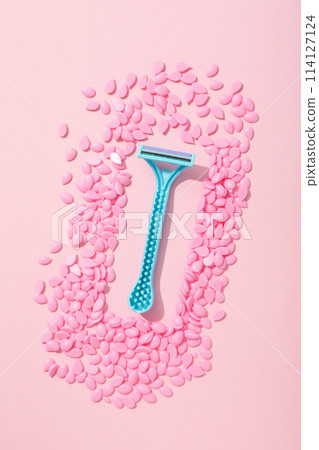 Wax granules for depilation with a razor on a pink background Wax granules for depilation with a razor on a pink background 114127124
