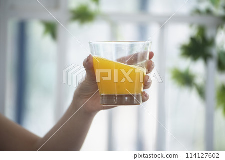 Women hands holding cold orange juice fresh fruit cool drinking. Asian women smile laugh look at camera health care home fitness lifestyle. Beautiful female pouring orange juice from cocktail bottle Women hands holding cold orange juice fresh fruit cool drinking. Asian women smile laugh look at camera health care home fitness lifestyle. Beautiful female pouring orange juice from cocktail bottle 114127602