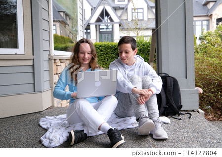 education, technology, school and internet concept - three smiling students with laptop, tablet pc and notebooks at school education, technology, school and internet concept - three smiling students with laptop, tablet pc and notebooks at school 114127804