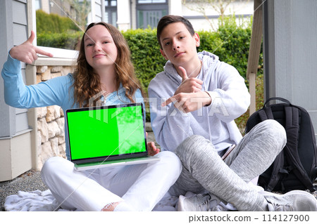 green screen chroma key teenagers study online sitting on the street with a laptop Girl and boy outdoor. Freelancer communicate on project, shopping online on wifi tablet. Working business process  114127900