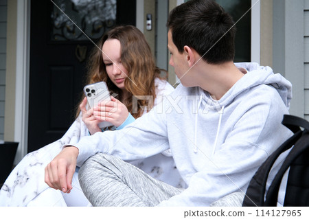 Young happy couple customers holding smartphone using mobile cell phone at home, doing online shopping in ecommerce app together, ordering food delivery, checking social media applications together. 114127965