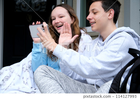 brother and sister communicate online wave hello laughter smile joy of communication sit on porch in blanket have fun go on vacation relax in a sanatorium adolescence leave the war in Ukraine brother and sister communicate online wave hello laughter smile joy of communication sit on porch in blanket have fun go on vacation relax in a sanatorium adolescence leave the war in Ukraine 114127993