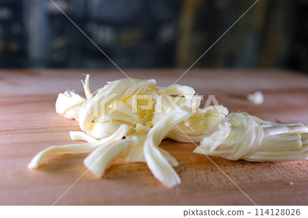 cut cheese women's hand manicure franch Cheese of suluguni smoked pigtail piece, moving sideways, close-up macro, top view 114128026