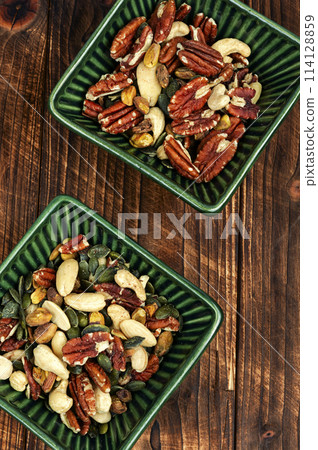 Mixed nuts in a bowl on wooden background. 114128859