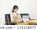 A woman checking her smartphone while using a laptop 114128877