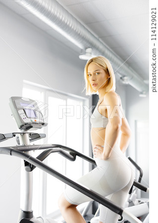 Young woman in sportswear working out at the gym. She is working out on stairway simulator Young woman in sportswear working out at the gym. She is working out on stairway simulator 114129021