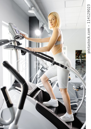 Young woman in sportswear working out at the gym. She is working out on stairway simulator Young woman in sportswear working out at the gym. She is working out on stairway simulator 114129023