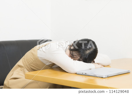 一位年輕女子厭倦了使用電腦並睡著了 一位年輕女子厭倦了使用電腦並睡著了 114129048