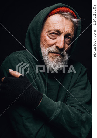 Homeless man dressed in green old clothing shivers from cold, tries to warm up. Homeless man dressed in green old clothing shivers from cold, tries to warm up. 114129105