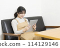 Young woman sitting on sofa and using tablet 114129146
