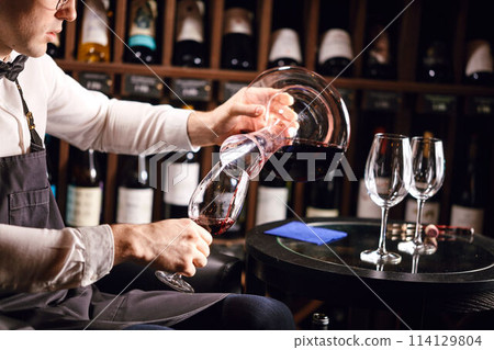 Wine taster or degustator pouring red wine into carafe to make perfect color Wine taster or degustator pouring red wine into carafe to make perfect color 114129804
