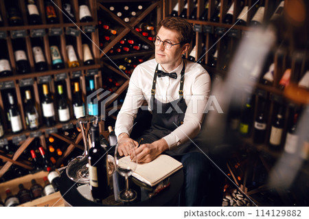 Wine taster writing in notepad information of wine origin and taste. 114129882