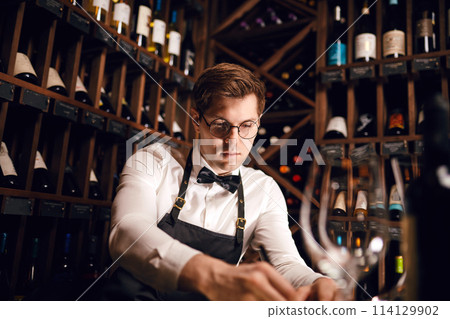 Wine taster writing in notepad information of wine origin and taste. Wine taster writing in notepad information of wine origin and taste. 114129902