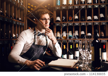 Sommelier offering bottle of red wine to customer Sommelier offering bottle of red wine to customer 114130035