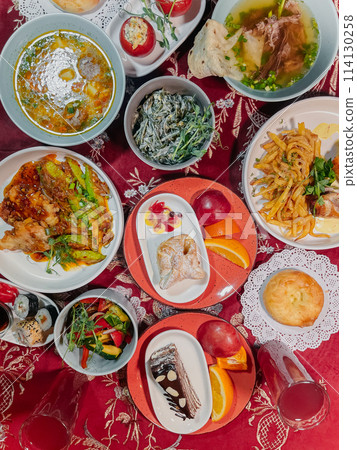 top view of Uzbek traditional dishes on a table with red tablecloth 114130258