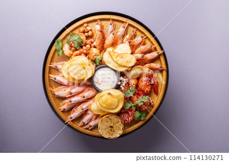 Fresh seafood platter with shrimps, lemon, and potato chips. 114130271