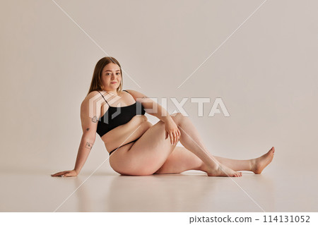 Strength of beauty. Young woman comfortable in her own skin, promoting positive body image against grey studio background Strength of beauty. Young woman comfortable in her own skin, promoting positive body image against grey studio background 114131052