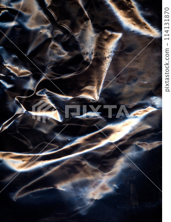 Creased surface. Crumpled material. Black color metallic overlay light refraction wrapped foil worn aged film glow texture grunge abstract background. Creased surface. Crumpled material. Black color metallic overlay light refraction wrapped foil worn aged film glow texture grunge abstract background. 114131870