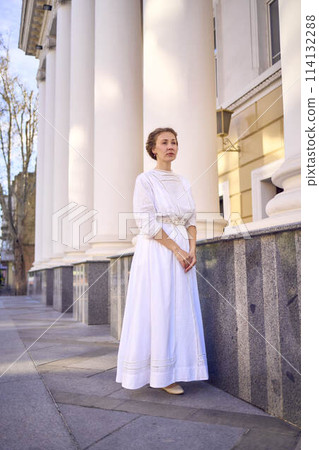 elegant middle age woman in white vintage dress near theater with antique colonnades elegant middle age woman in white vintage dress near theater with antique colonnades 114132288