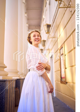 elegant middle age woman in white vintage dress near theater with antique colonnades elegant middle age woman in white vintage dress near theater with antique colonnades 114132300