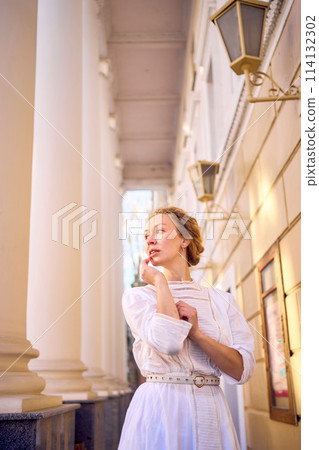 elegant middle age woman in white vintage dress near theater with antique colonnades elegant middle age woman in white vintage dress near theater with antique colonnades 114132302