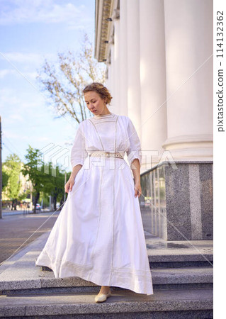 elegant middle age woman in white vintage dress near theater with antique colonnades elegant middle age woman in white vintage dress near theater with antique colonnades 114132362
