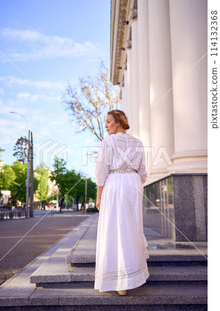 elegant middle age woman in white vintage dress near theater with antique colonnades elegant middle age woman in white vintage dress near theater with antique colonnades 114132368