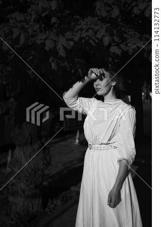 elegant middle age woman in a white vintage dress against the background of historical buildings in the morning light 114132773