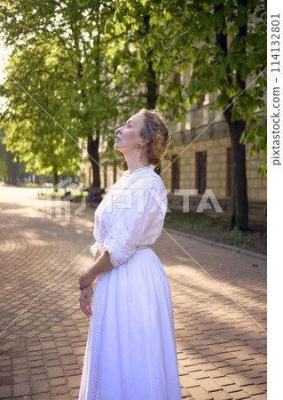 chic middle age woman in a white vintage dress in a sunlit alley chic middle age woman in a white vintage dress in a sunlit alley 114132801