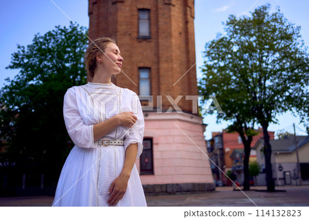 chic young woman in a white vintage dress on the square near the historic water tower in Vinnytsia chic young woman in a white vintage dress on the square near the historic water tower in Vinnytsia 114132823