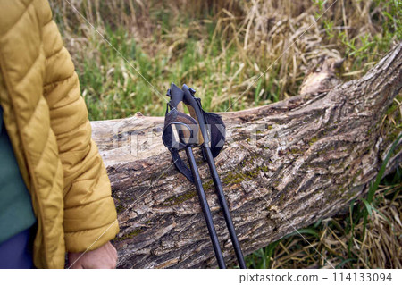 elderly woman rests on the river bank after Nordic walking exercise 114133094