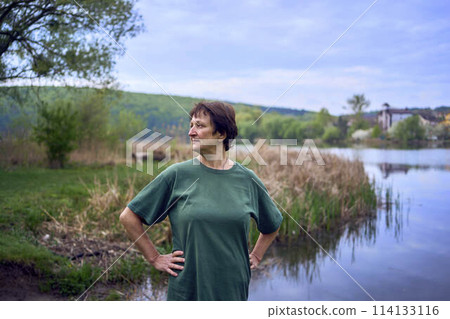 old woman doing exercises in the morning on the river bank, a bicycle and a yogamat next to her old woman doing exercises in the morning on the river bank, a bicycle and a yogamat next to her 114133116