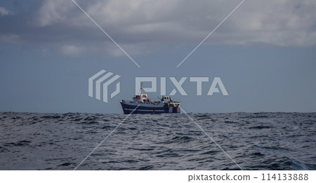 Fishing trawler conducts industrial trawl fishing in the ocean. Fishing trawler conducts industrial trawl fishing in the ocean. 114133888