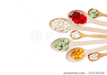 Top view Variety of vitamin and mineral pills in wooden spoon on Colored background. Top view of assorted pharmaceutical medicine pills. Dietary supplement healthcare product 114134328