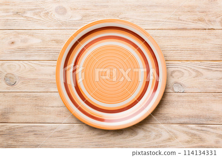 Top view of empty orange plate on wooden background. Empty space for your design 114134331
