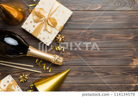 Flat lay composition of Champagne bottle gift box ribbons and confetti on colored background. Flat lay, top view holiday concept 114134579