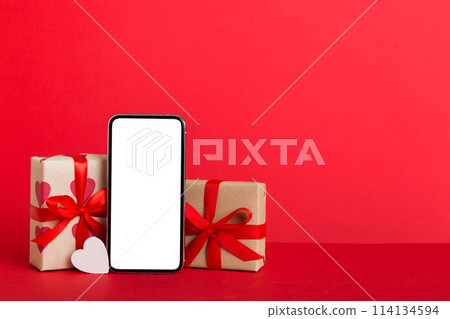mobile phone with blank screen on colored background with hearts, calendar and gift box, valentine day concept perspertive view flat lay mobile phone with blank screen on colored background with hearts, calendar and gift box, valentine day concept perspertive view flat lay 114134594