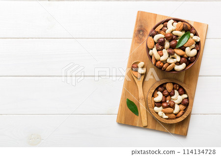 Assortment of nuts in wooden bowl on colored table. Cashew, hazelnuts, walnuts, almonds. Mix of nuts Top view with copy space Assortment of nuts in wooden bowl on colored table. Cashew, hazelnuts, walnuts, almonds. Mix of nuts Top view with copy space 114134728