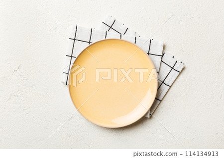 Top view on colored background empty round yellow plate on tablecloth for food. Empty dish on napkin with space for your design 114134913