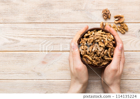 Woman hands holding a wooden bowl with walnut nuts. Healthy food and snack. Vegetarian snacks of different nuts 114135224