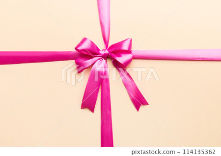 Top view of purple ribbon rolled and pink bow isolated on colored background. Flat lay with copy space Top view of purple ribbon rolled and pink bow isolated on colored background. Flat lay with copy space 114135362