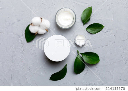 Organic cosmetic products with cotton flower and green leaves on cement background. Flat lay Organic cosmetic products with cotton flower and green leaves on cement background. Flat lay 114135370