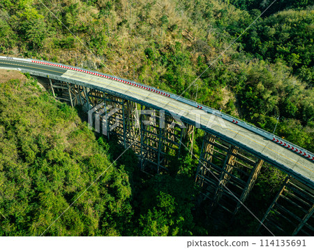.Bridge over forest river under blue sky with green landscape and mountain view with trees.. .Bridge over forest river under blue sky with green landscape and mountain view with trees.. 114135691