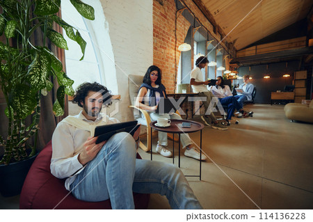 Innovative business environment. Young multiethnic people, men and people meeting in modern office space and working, doing own tasks 114136228