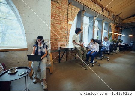 Young entrepreneurs and students in co-working space working and cooperating. Cozy, comfortable professional atmosphere Young entrepreneurs and students in co-working space working and cooperating. Cozy, comfortable professional atmosphere 114136239