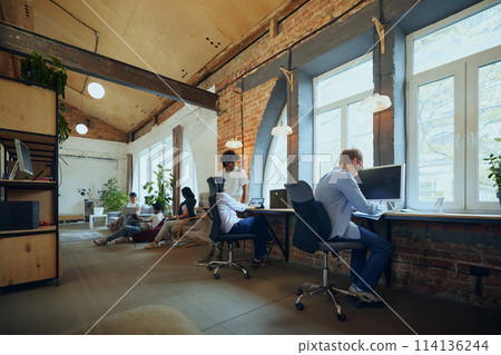 Interactive co-working space. Bustling co-working environment with young multiethnic people working and studying 114136244