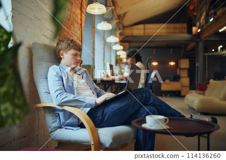 Dynamic workspace. Lively coworking space filled with young people, students and employees engaged in various activities, working, studying 114136260