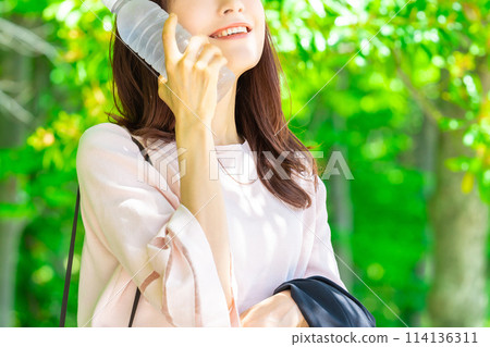 Woman cooling off by holding a plastic bottle to her cheek - heat stroke prevention Woman cooling off by holding a plastic bottle to her cheek - heat stroke prevention 114136311