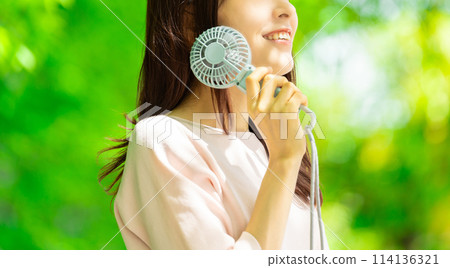 Woman cooling off with a handheld fan - summer heatstroke prevention Woman cooling off with a handheld fan - summer heatstroke prevention 114136321