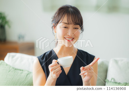 Middle-aged woman drinking coffee in the living room Middle-aged woman drinking coffee in the living room 114136908
